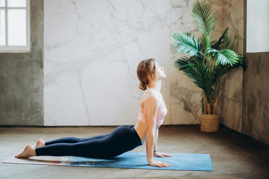 A female doing the yoga cobra pose on a yoga mat
