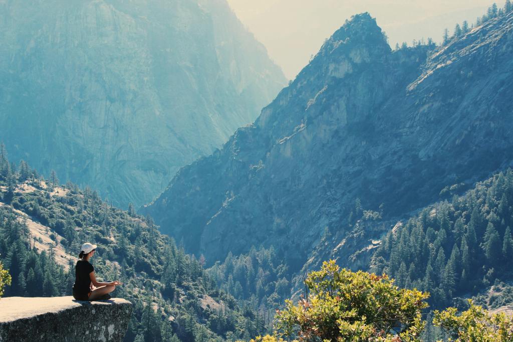 person meditating on a mountain surrounded by nature
