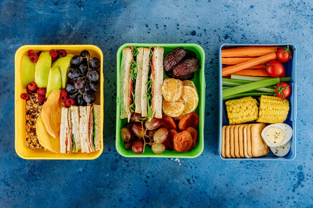 Lunch boxes full of healthy vegetables, fruits, sandwiches, eggs, and more