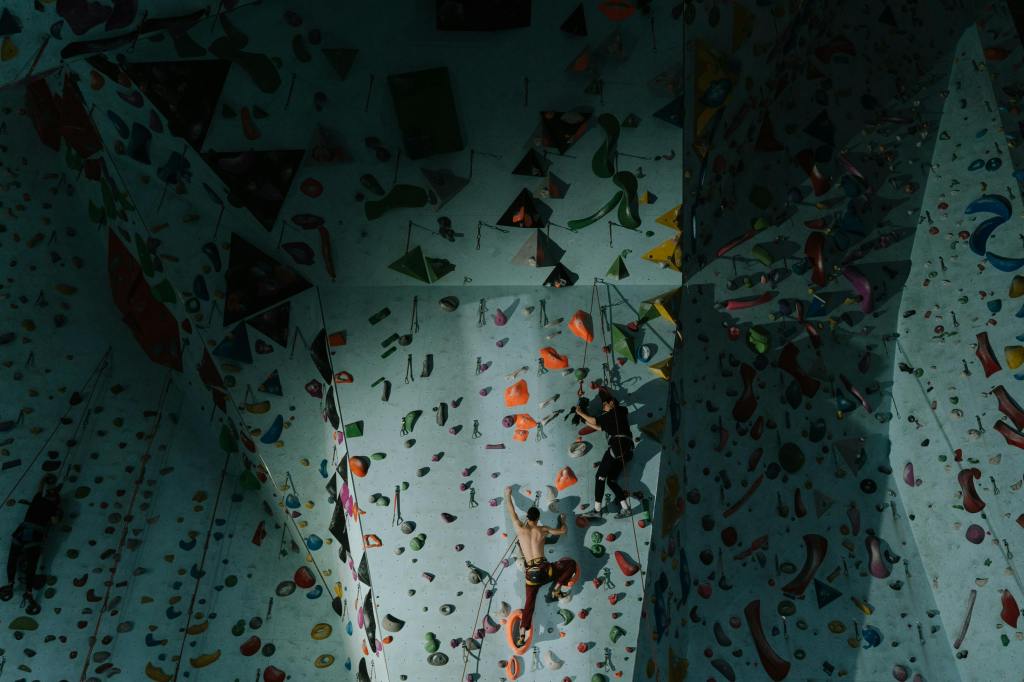 a large bouldering wall with two people climbing it