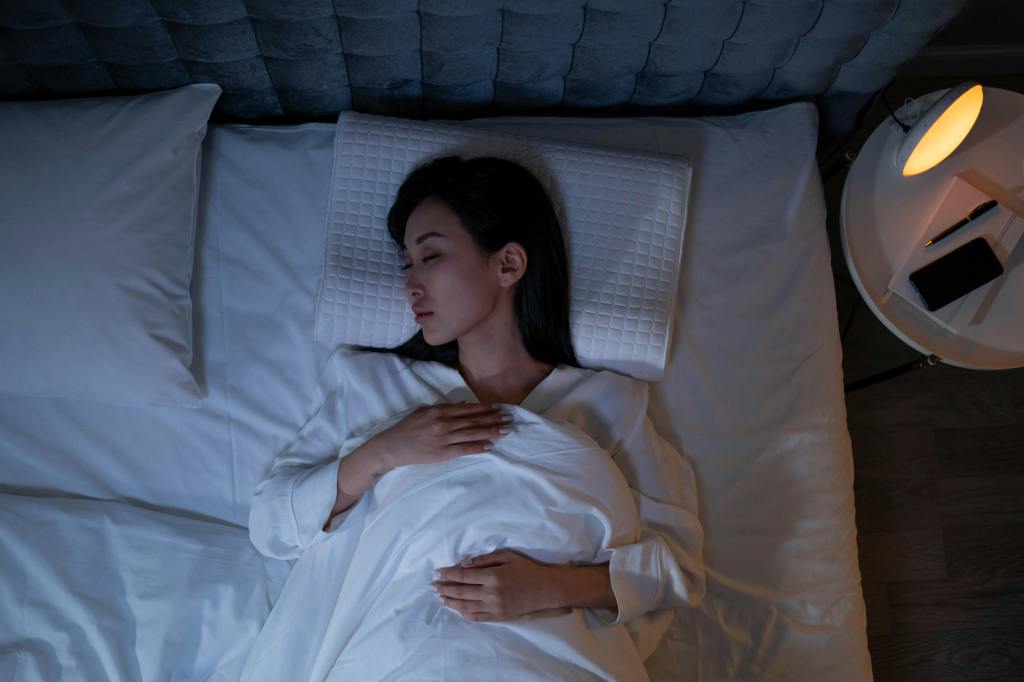 A girl sleeping in a comfortable bed at nighttime.  