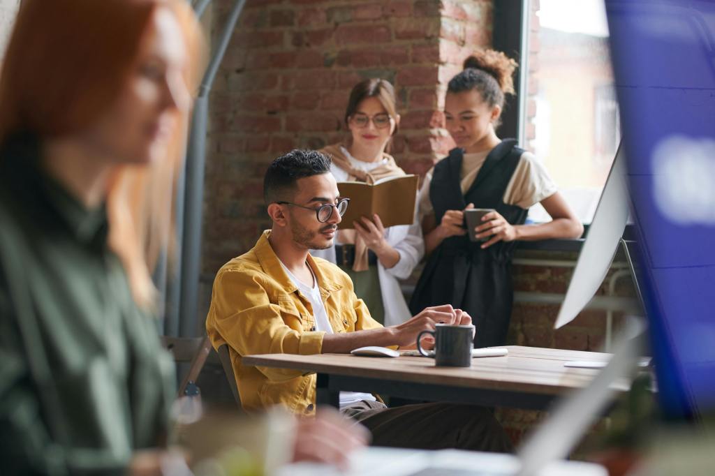 a young man surrounded by other young adults pondering at a coffee table looking professional