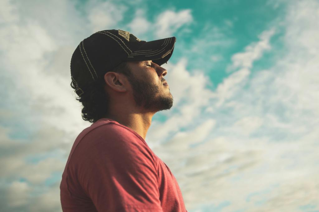 A young man breathing in and out while being outside.