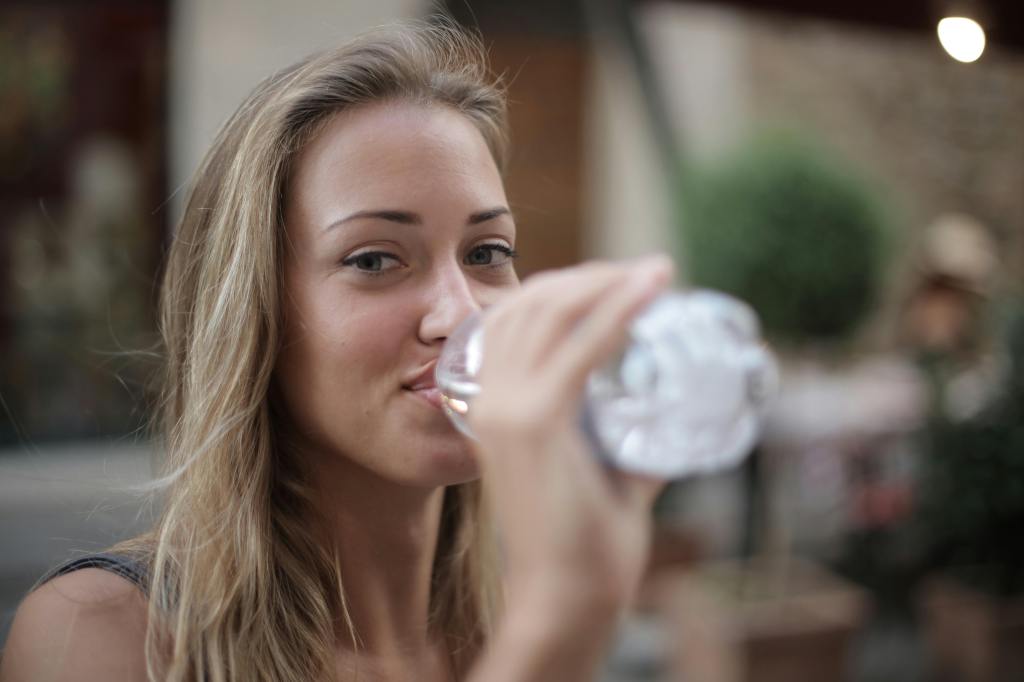 A young woman drinking a bottle of water.
