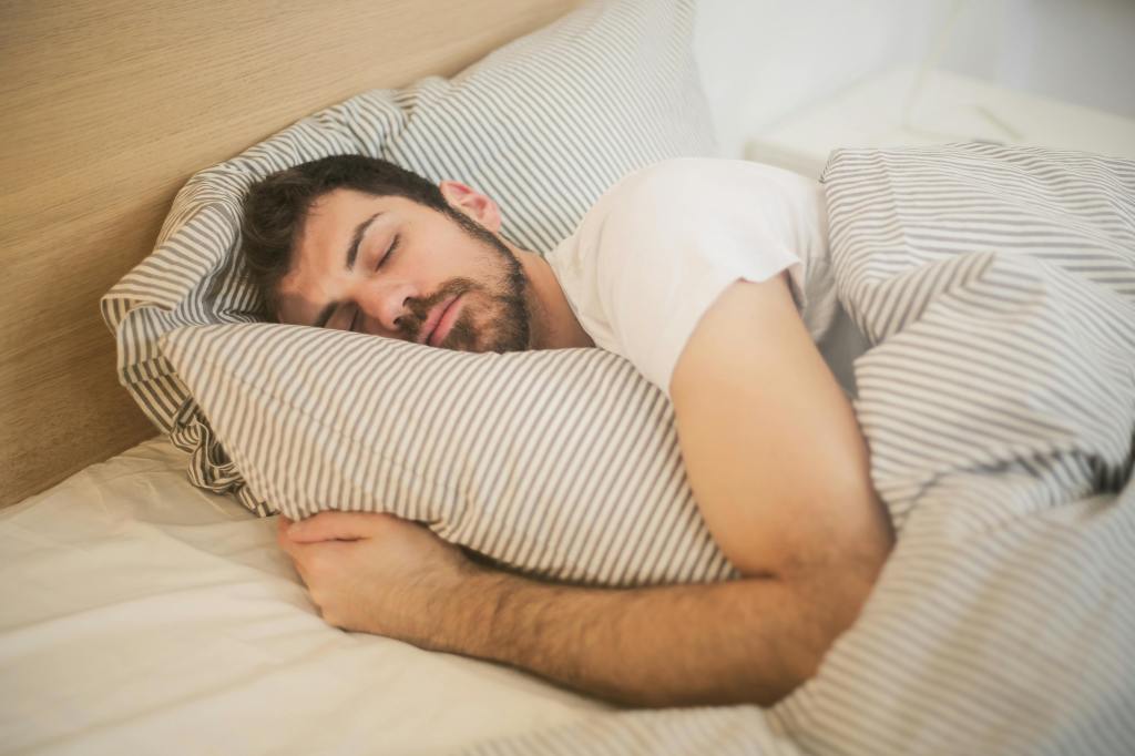 A man peacefully sleeping in a white bed