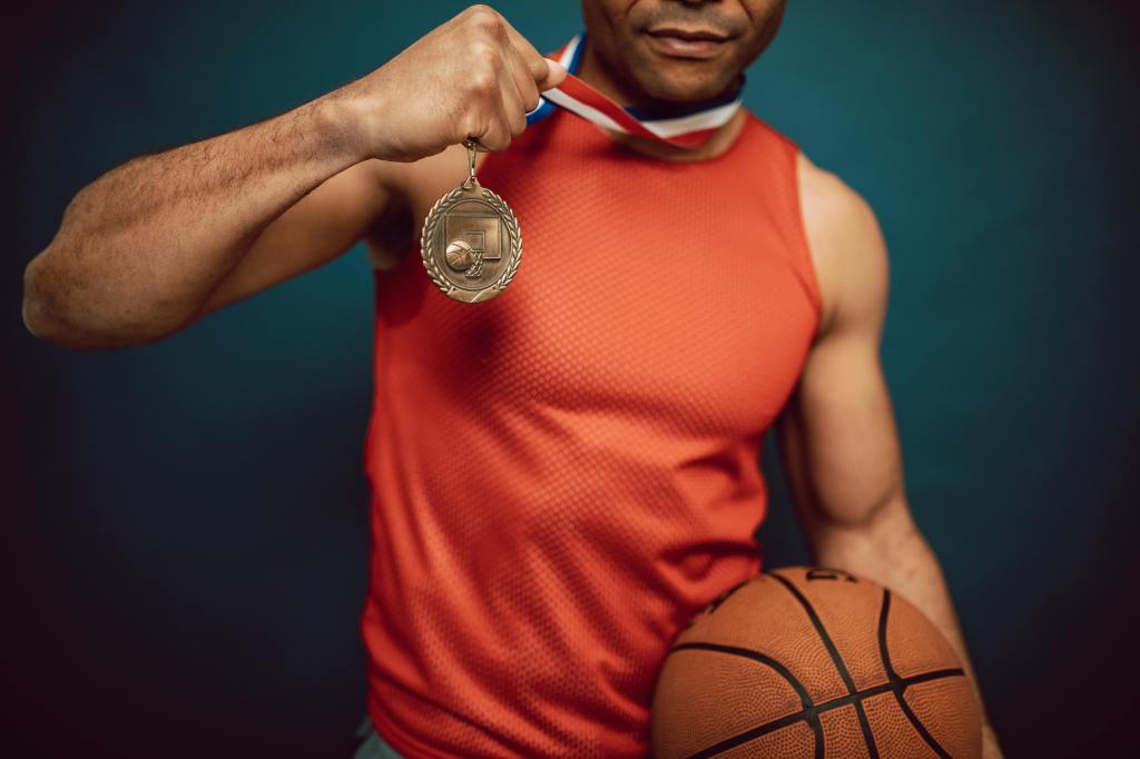 A person holding up their medal and basketball
